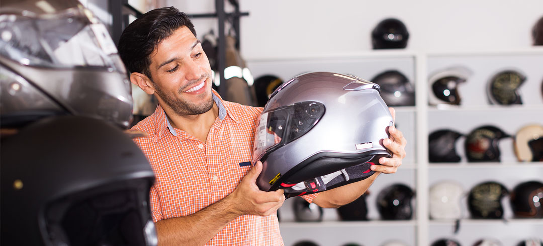 Motociclista sosteniendo un casco en una tienda de equipamiento para motos
