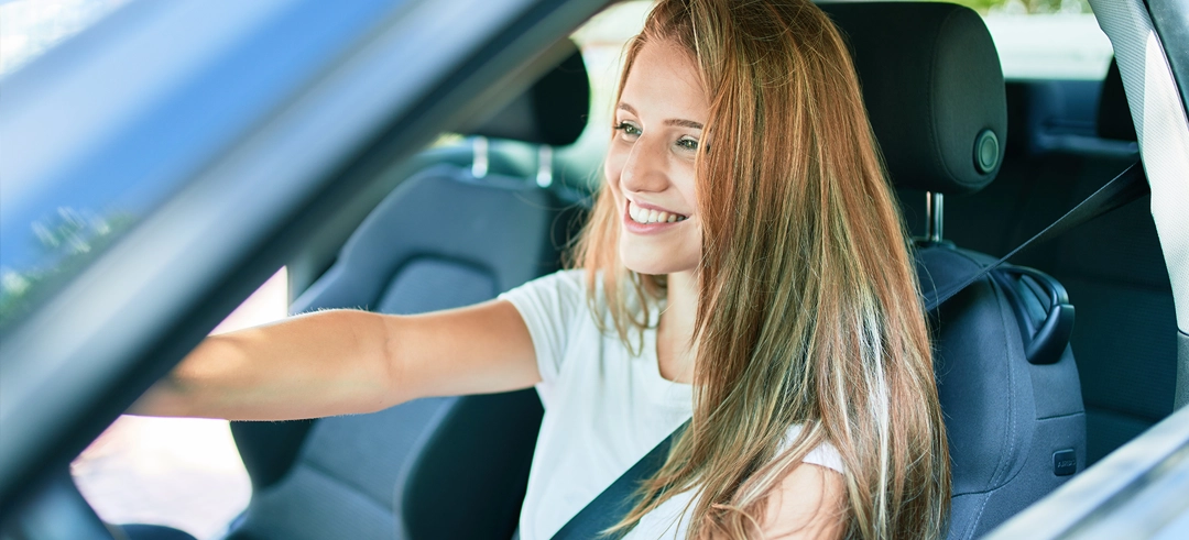 Chica joven conduciendo un coche desde el asiento del conductor