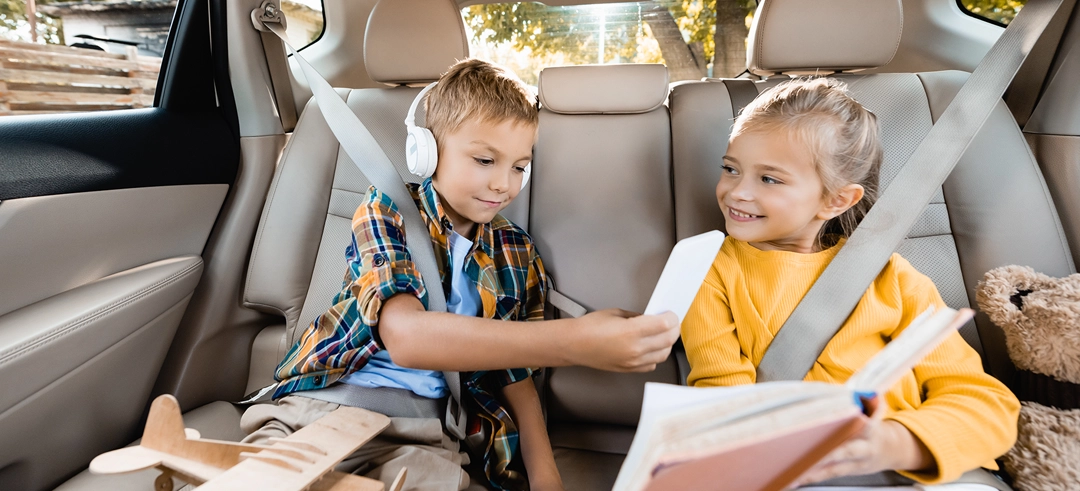 Niño y niña sentados con el cinturón en el asiento trasero de un coche 