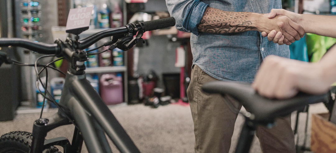 Dos personas dándose la mano en la compraventa de una bicicleta
