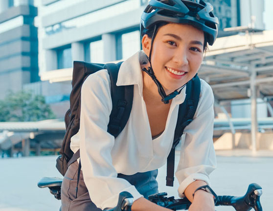 Persona feliz montada en bicicleta con el casco puesto y mochila