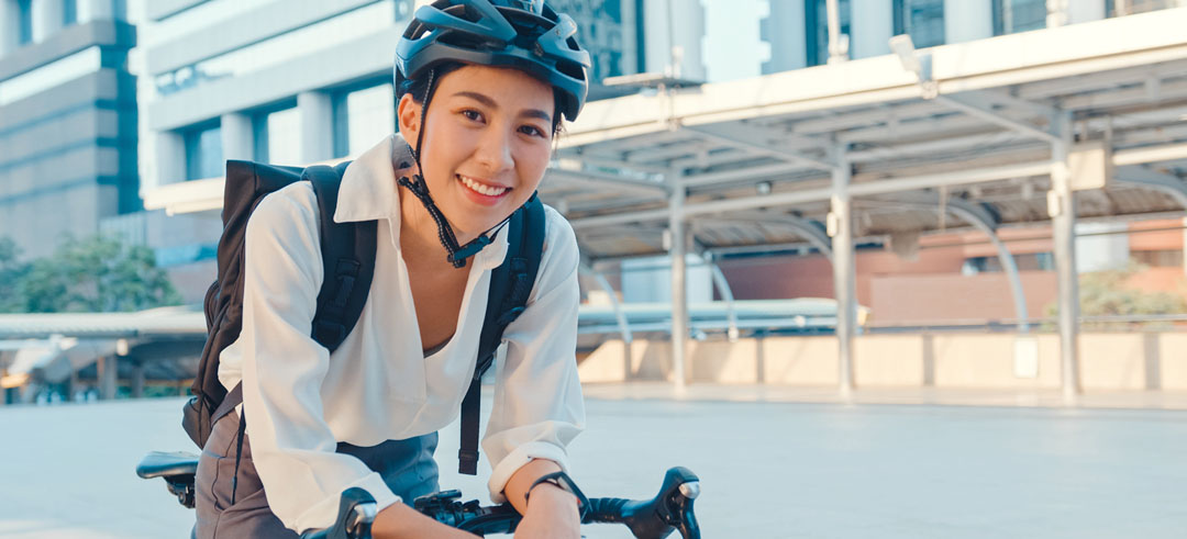 Persona feliz montada en bicicleta con el casco puesto y mochila