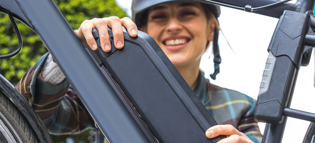 Chica colocando la batería en una bicicleta eléctrica