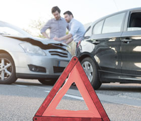 Dos personas rellenando un parte de accidentes tras un choque de coche