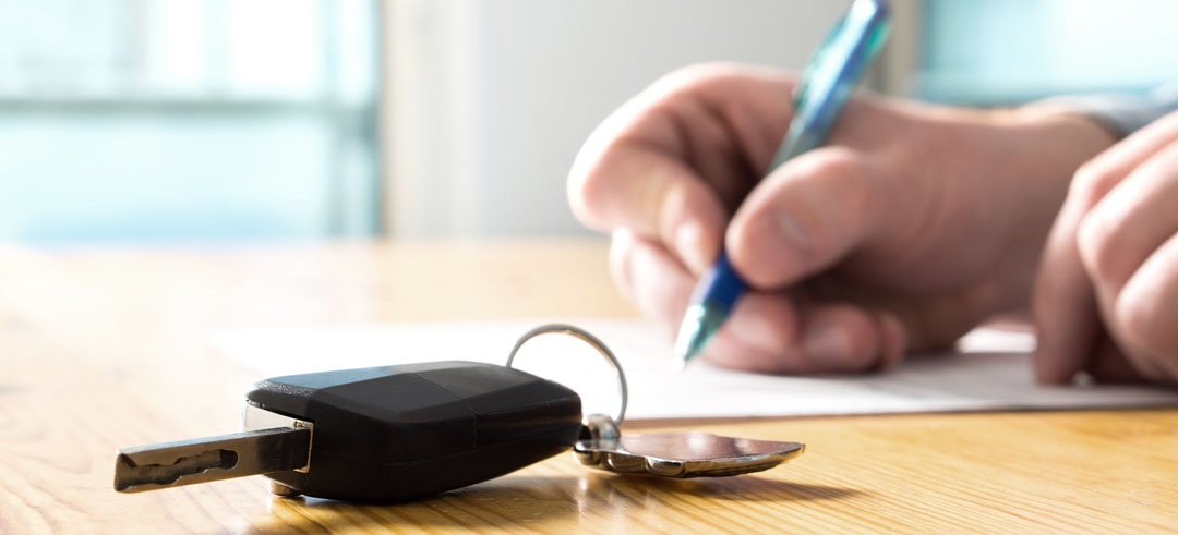 Firma de documentos para una compraventa de un coche con la llaves encima de la mesa